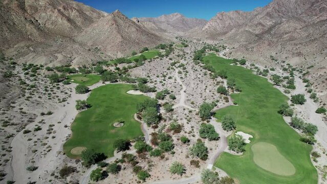 Aerial of golf course nestled amongst dramatic desert mountains in La Quinta