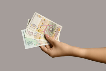 Female hand holding Bulgarian lev banknotes on grey background