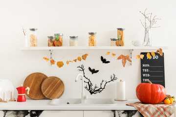 Interior of light kitchen decorated for Halloween with counters and shelf
