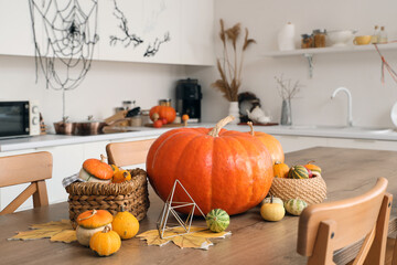 Halloween pumpkins with baskets and leaves on table in kitchen, closeup