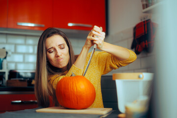 Woman Holding a Knife Ready to Carve a Halloween Pumpkin. Stressed lady feeling bored thinking what...