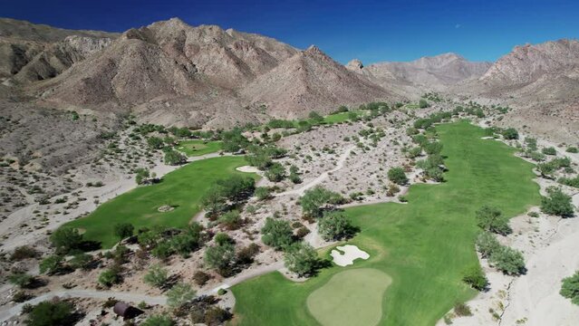 Aerial of golf course nestled amongst dramatic desert mountains in La Quinta