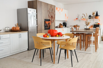 Interior of light kitchen decorated for Halloween with counters and dining tables