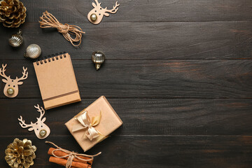 Blank paper calendar, gift box and Christmas decorations on black wooden background