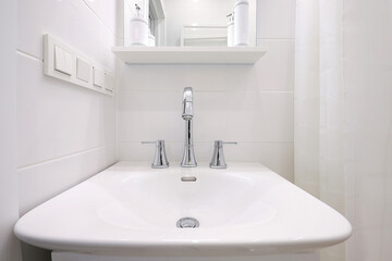 Chrome faucet with white ceramic sink in the bathroom