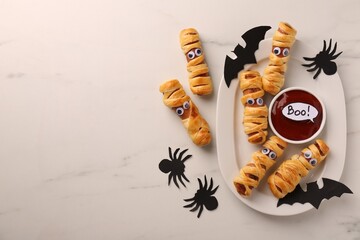 Flat lay composition with tasty sausage mummies for Halloween party on white marble table. Space for text