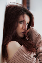 Sensual young woman leans, red hair teases lips