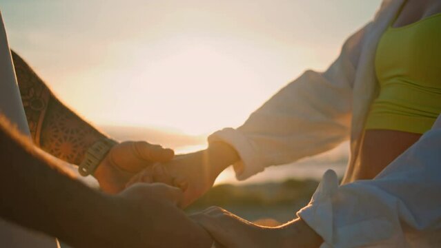 Love couple connecting hands bright sun beach closeup. Lights between people