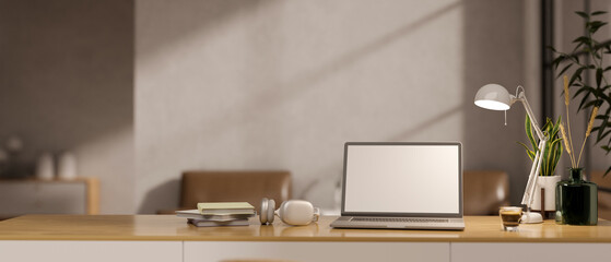 A wooden desk in a minimalist home office with a white-screen laptop mockup and accessories.