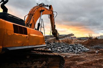 Powerful crusher destroys armored cement leftovers at sunset