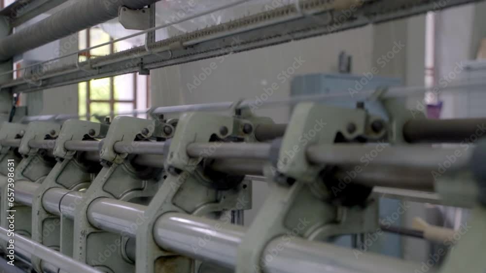 Poster close-up view of a machine weaving fabric rapidly with great precision.