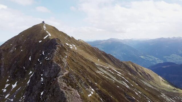 Cinematic aerial of alps mountain top with old wooden chapel on steep peak. Beautiful alpine scenery with valley in distance landscape view. Kellerjoch, Austria. Drone flying along ridge to summit 4K