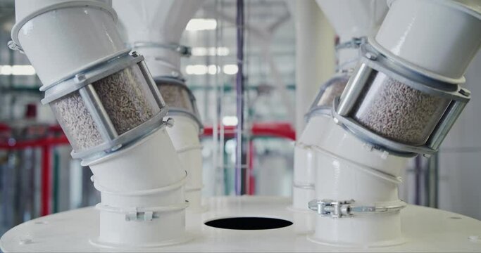Dolly shot of grain pouring through inspection tubes at a state-of-the-art grain mill facility, showcasing large-scale food production on an industrial level. Concept of high-tech food production.