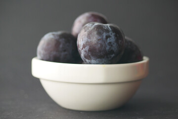 Fresh plums in a bowl on table 