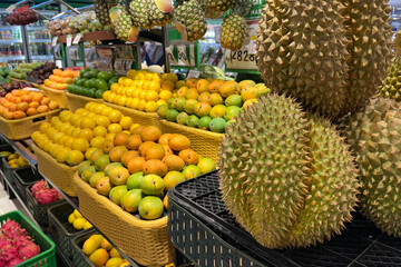 Various type of fresh fruits arrange neatly in grocery store. Durian, mango, lemon and orange on rack.