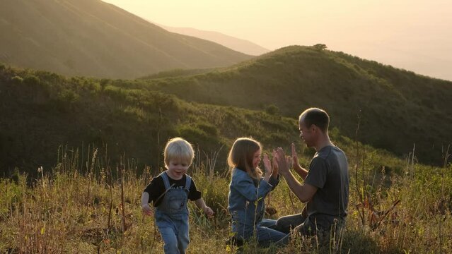 Dad has fun playing with his children in nature at sunset.