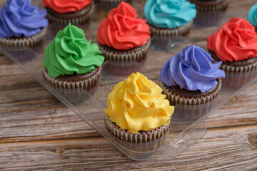 Multicolored cupcakes on wooden table. Colorful desserts.