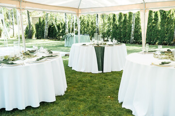 Open -air wedding banquet. The table is decorated with white plates and premium glasses for wine