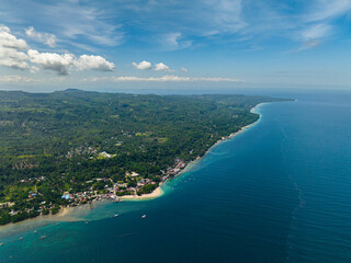 Coastline area with a white sandy beach and blue sea. Blue sky and clouds. Samal Island. Davao, Philippines.