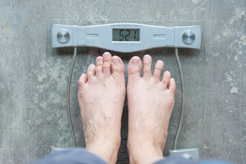 Woman weighing her feet on a bathroom scale for weight loss and diet progress