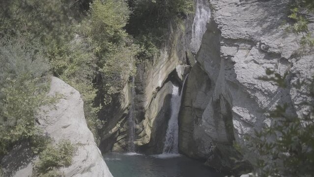 Shot of the waterfall near Bogova Albania on a sunny day with no people and clear water with rocks and plants around LOG
