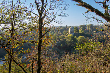 Fototapeta premium Medieval ruins of fort at Crozant in Creuse, France. An early morning view, through trees, across the valley and river confluence of the Sedelle with rocks in the foreground.