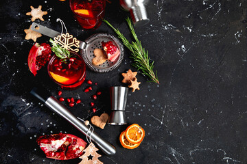 Winter christmas cocktail with pomegranate and rosemary in a glasses on black background. Top view