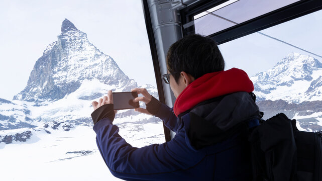 Young tourist blogger travel with matterhorn snow peak view and  taking photo by smartphone with snow mountain at Switzerland