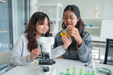 Group of young asian schoolgirls learning research and doing experiment in chemistry classroom. Fun...