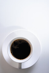 top view, a cup of coffee on a light background, a close-up view in a light dish. Place for inscription