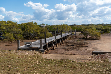 Rustic wooden jetty on a tidal creek with mangroves. Queensland, Australia 