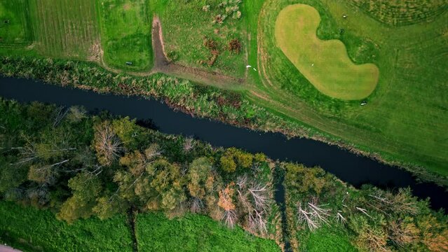 Moving top shot of a golf course in Espoo, Finland, passing a small river