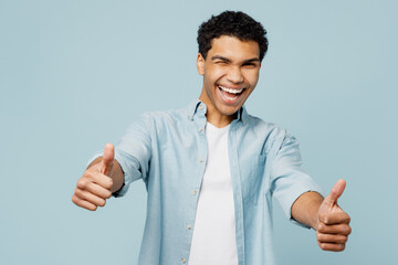 Young satisfied smiling happy man of African American ethnicity wear shirt white t-shirt casual clothes show thumb up like gesture isolated on plain pastel light blue cyan background studio portrait.