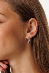 Beautiful young girl with fresh healthy skin. Woman advertise ear-rings. White background. Earrings, ear caffs closeup. Blond european woman with long hair with big lips, pretty smile. Cosmetology