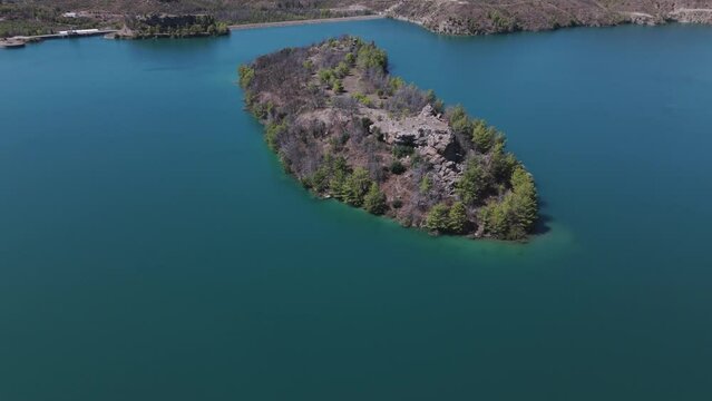 Aerial view over small woodland island in the stunning Green lake turquoise waters in the Taurus mountains of Turkey
