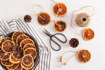 Dried orange slices on a metal vintage tray, scissors, skein of thread for homemade needlework. Top view. Flat lay.