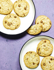 homemade chocolate chip cookies in plate on purple grunge background