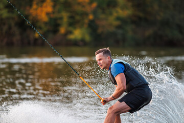 An athlete performs a trick on the water. Park at sunset. Wakeboard rider