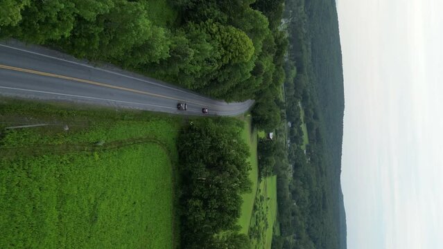 Aerial view of the road along which the car drives in the forest. Travel and tourism by car in the scenic cities of the country side. High quality 4k footage