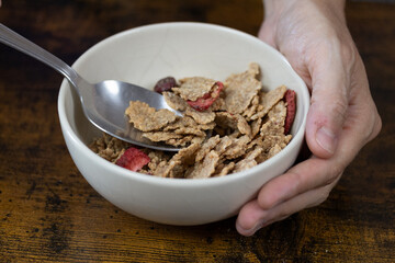 main d'une personne tenant un bol de céréales dans ses mains
