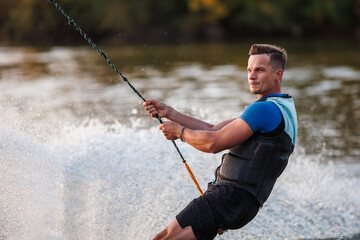 An athlete performs a trick on the water. Park at sunset. Wakeboard rider