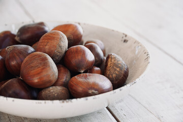 Chestnuts in a bowl on a wooden table with space for text.
