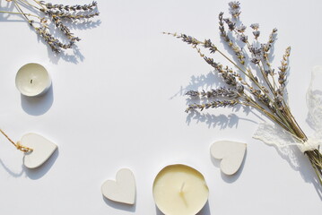  Lavender branches, wooden white hearts and white candles on a white background. Top view, background, postcard, space for text, copy.
