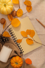 Autumn background with dry leaves, pumpkins and decorative notebooks on vintage fabric. Top view, autumn concept waiting for the upcoming Thanksgiving holiday