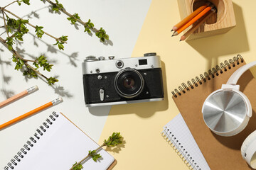 Vintage camera, notepads and headphones on light background, top view