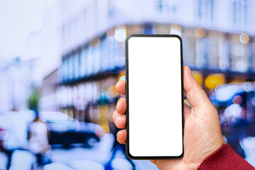 Mockup blank white screen of smartphone, male hand holding modern black cellphone with template screen for your logo or design,city blurred street in the background.