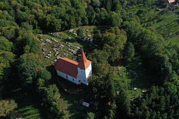 Flying above old whitewashed reformed church and aerial. Medieval landmark, Bicfalau, Szeklerland, Romania