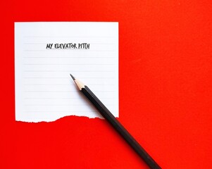 On copy space orange background, pencil writing on paper MY ELEVATOR PITCH, to create brief, persuasive speech to spark interest in what you or organization does, as short as elevator ride 30 seconds