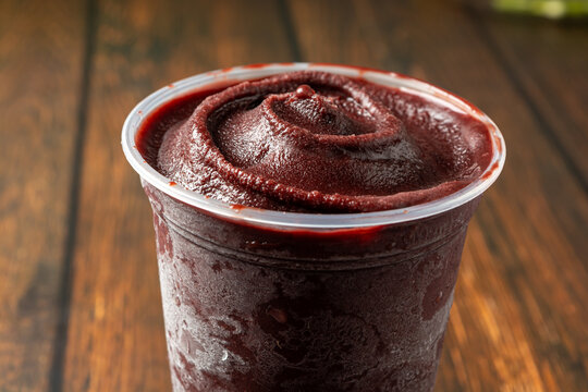 close up açai in a plastic cup over wooden table. ready for delivery