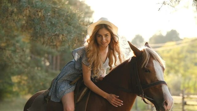 A young beautiful woman sits on a horse in the autumn forest. Horseback ride. Preparing for a show jumping competition.
